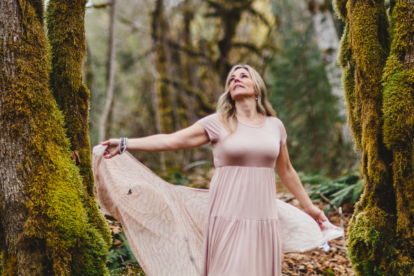 dennyse holding the sides of her pink dress in forest